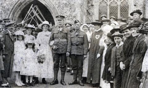 Black and white photograph of a group of people, men in uniform and women in dress clothes.