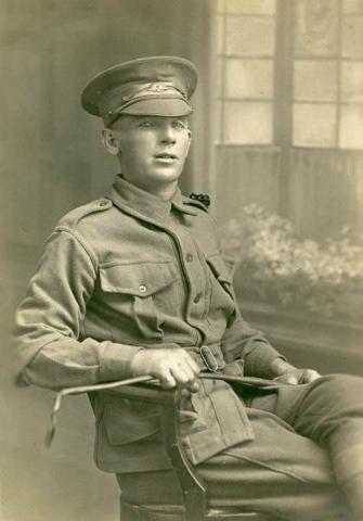 Sepia photograph of soldier in uniform reclining on  a chair.