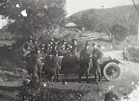 Black and white photo of soldiers gathered around a motor car. 