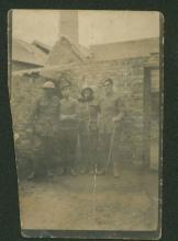 Faded sepia photograph of four men in uniform.